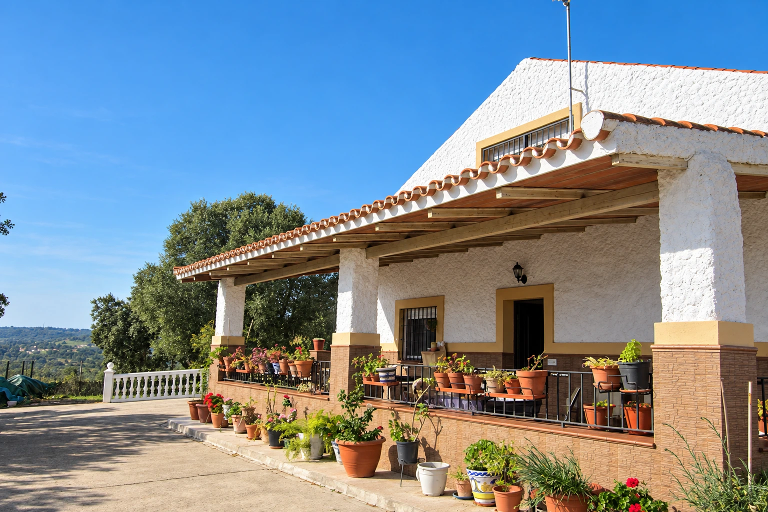 Casa principal de La Encina, con su porche, sus macetas y las encinas al fondo